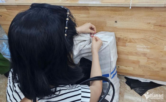 Người dân cẩn thận buộc chặt các bao tải, túi đựng tiền sau khi nhận bồi thường. Ảnh: Thành Huế