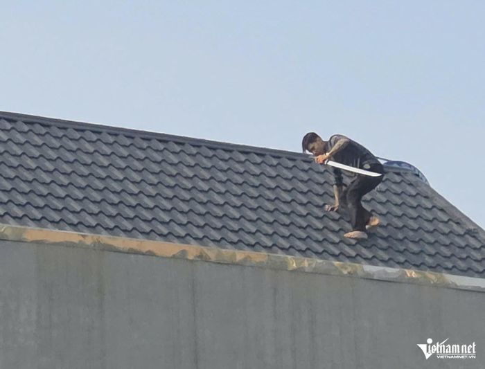 Một trong 2 thanh niên cầm kiếm cố thủ trên nóc nhà từ trưa nay 26/10. 