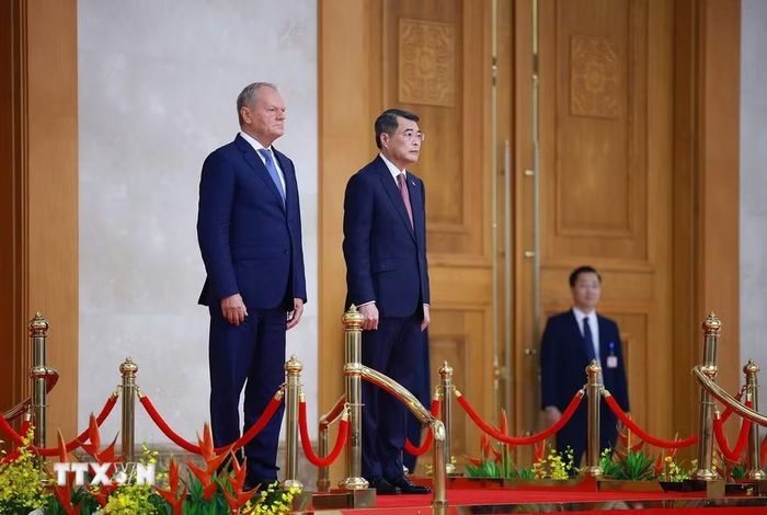 Thủ tướng Lê Minh Hưng và Thủ tướng Ba Lan Donald Tusk thực hiện nghi lễ chào cờ. (Ảnh: Dương Giang/TTXVN)