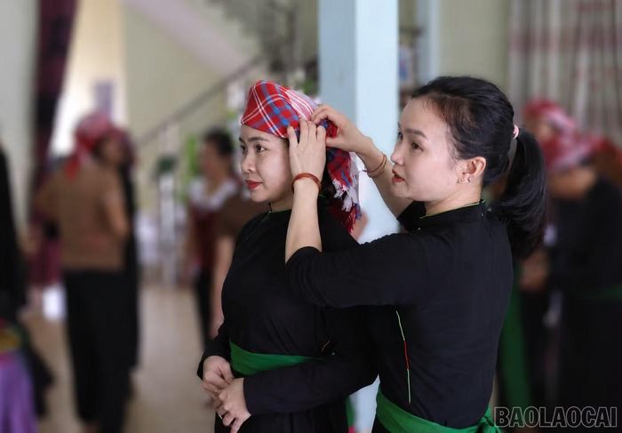 Chị Hà Thị Minh mặc thử bộ áo dài cưới cho cô gái người Tày ở xã Võ Lao.