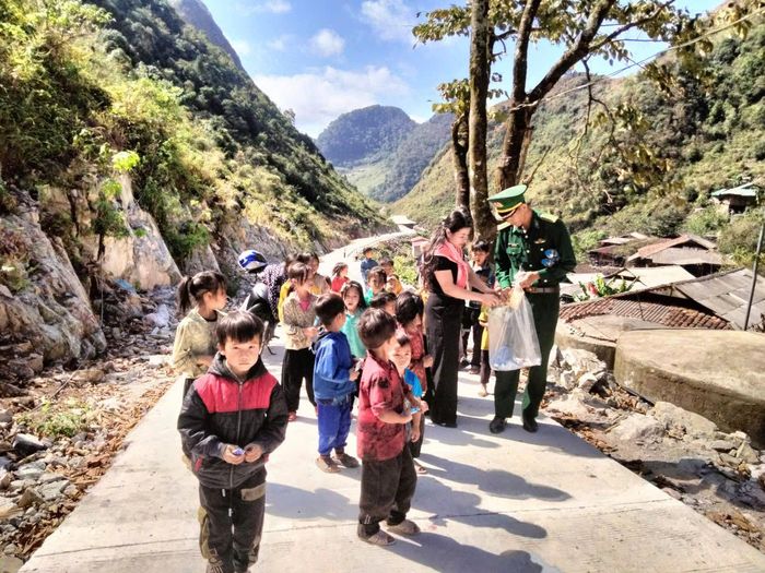 Cán bộ Đồn Biên phòng Xuân Trường phát quà cho các cháu bé xóm Cà Lò. Ảnh: Mai Hương