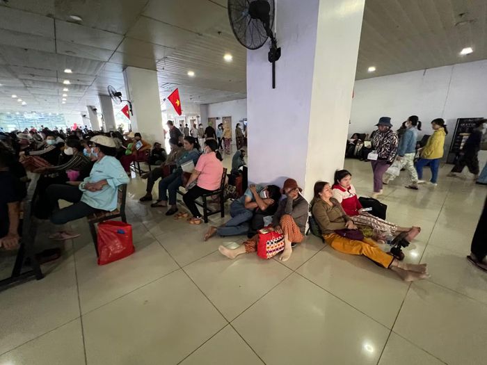Ghế đã kín nên người đến khám bệnh và người dân ngồi xuống đất.