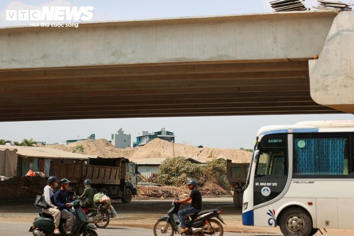 Công trường nằm ngay cạnh Quốc lộ 6, tuyến đường có lưu lượng phương tiện lớn. Xe tải, xe khách và ô tô cá nhân vẫn nối đuôi nhau qua khu vực, trong khi các nhà thầu triển khai nhiều hạng mục xây dựng sát mặt đường.