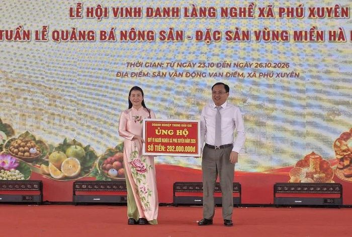 Lãnh đạo UBND xã Phú Xuyên trao biểu trưng doanh nghiệp trúng đấu giá sản phẩm làng nghề truyền thống ủng hộ Quỹ vì người nghèo năm 2026 với số tiền 202 triệu đồng. Ảnh: PV