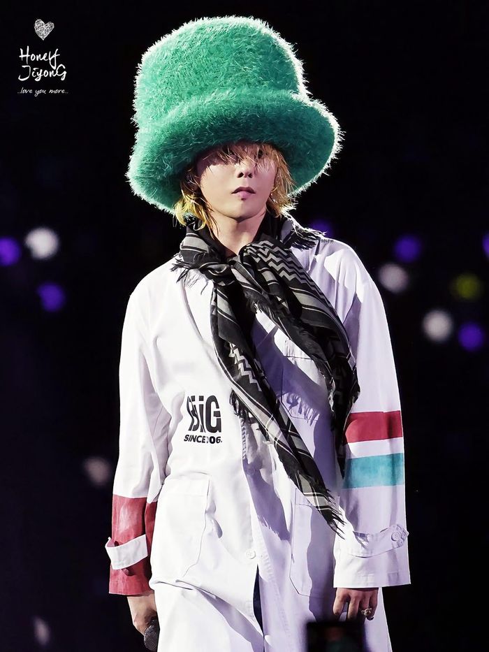 Mũ lông chóp cao - món phụ kiện gắn bó với G-Dragon cả chục năm nay - tiếp tục được anh sử dụng trong concert. Đi cùng chiếc mũ lông xanh ấn tượng là lối phối đồ layering, thể hiện sự phóng khoáng của đường phố với áo thun oversized, quần jeans, boots và khăn choàng.