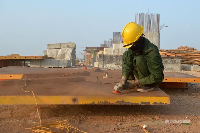 Công nhân sử dụng máy mài xử lý bề mặt cấu kiện thép tại công trường. Ảnh: Tuấn Anh