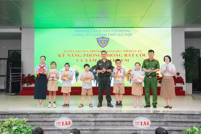 Cảnh sát cơ động và Ban Giám hiệu nhà trường trao tặng tài liệu tuyên truyền pháp luật cho các em học sinh.