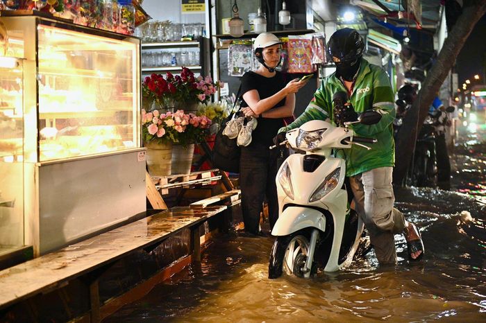 Nước dâng nửa bánh xe, nhiều phụ huynh, dân văn phòng phải dừng vào vị trí cao, chờ nước rút rồi mới tiếp tục hành trình, không mạo hiểm chạy xe qua đoạn ngập sâu. Nhiều hàng quán ven đường phải kê cao đồ để tránh nước tràn vào trong.