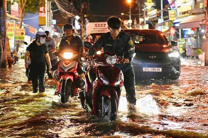  Lực lượng dân quân tự vệ phường giúp người dân dắt xe qua đoạn đường nước cao.