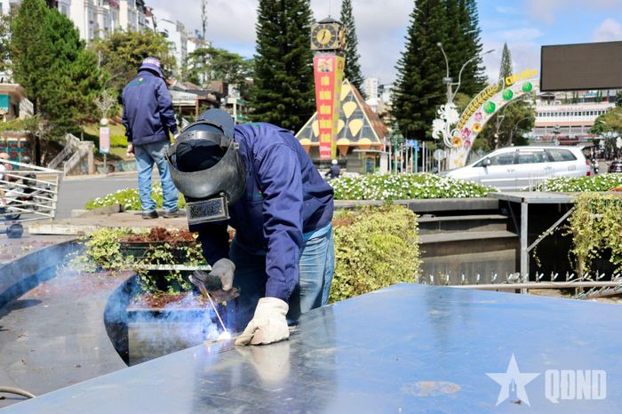 Công nhân Công ty Dalat Hasfram thi công hệ thống lắp đặt tiểu cảnh hoa tươi tại Đài phun nước. 