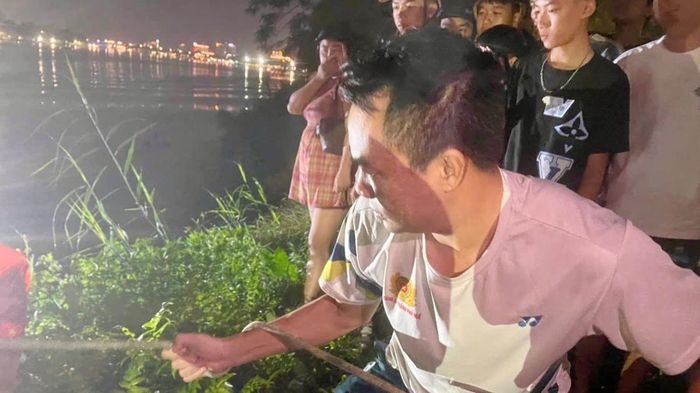 Lực lượng Công an và người dân hỗ trợ đưa thanh niên lên bờ.