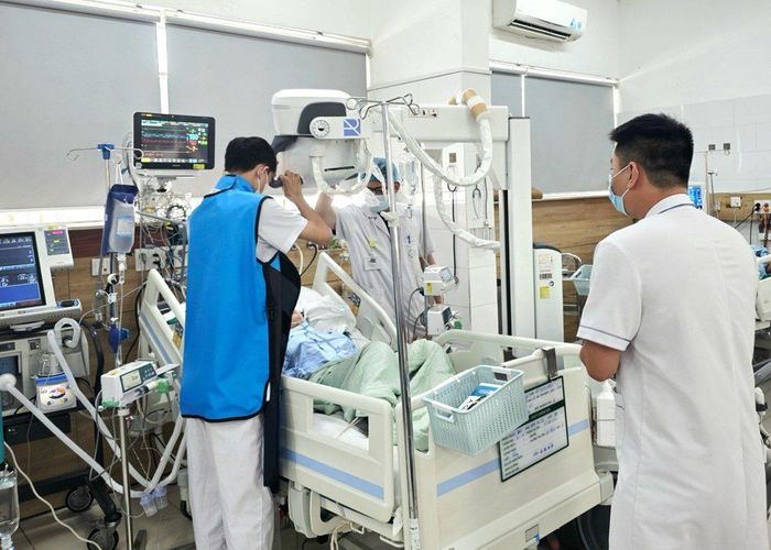  Bác sĩ chụp X-quang tại giường đánh giá tình trạng phổi của người vợ sau vụ cháy. Ảnh: NGUYÊN HÀ 