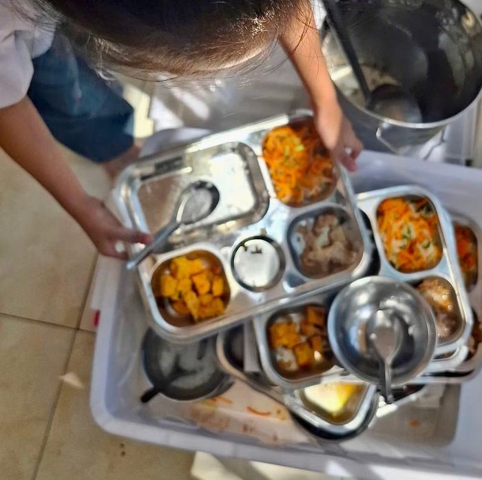  Học sinh tiểu học ở Hà Nội đổ thức ăn thừa vào thùng rác sau bữa ăn bán trú. 