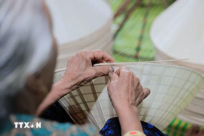 Nghệ nhân làm nón tỉ mỉ khâu lá trên khuôn. (Ảnh: Lê Đông/TTXVN)