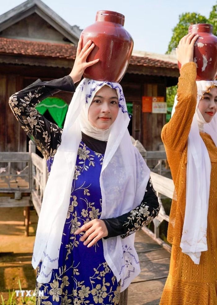 Khi ra ngoài, hoặc nhà có người lạ, phụ nữ Chăm Islam thường mặc trang phục kín đáo, kết hợp áo dài tay và khăn phủ tóc. (Ảnh: Khánh Hoà/TTXVN)