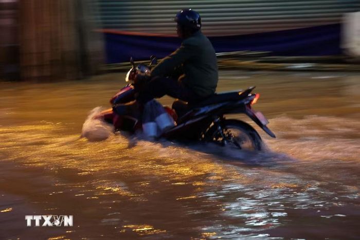 Các phương tiện di chuyển trên đường Nguyễn Bình đoạn ngập gần nửa mét do triều cường lên cao chiều 27/10. (Ảnh: Hồng Đạt/TTXVN)