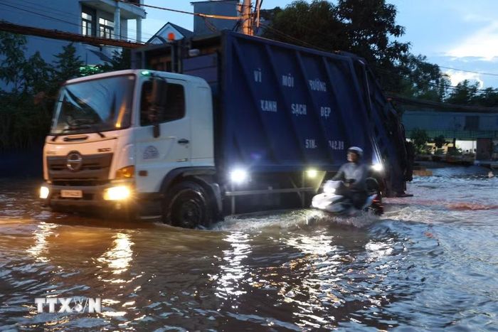 Các phương tiện di chuyển trên đường Nguyễn Bình đoạn ngập gần nửa mét do triều cường lên cao chiều 27/10. (Ảnh: Hồng Đạt/TTXVN)