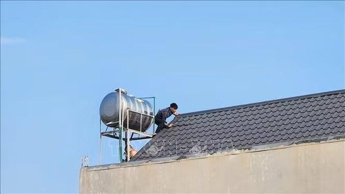 2 người đàn ông bỏ chạy lên mái nhà, mang theo hung khí gồm kiếm, gậy gỗ… và cố thủ trong nhà. Ảnh: TTXVN phát