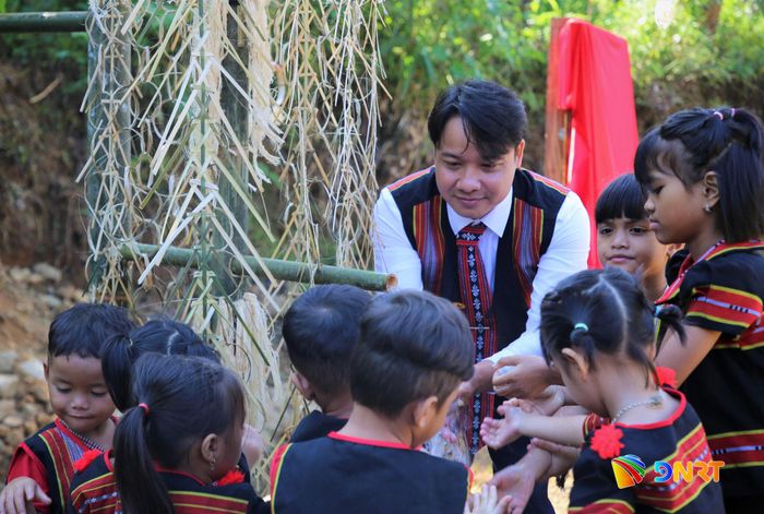 Người dân và trẻ em M'Nông ở khu dân cư Bằng La hứng trọn dòng nước mát bên máng nước vừa hình thành. Ảnh: ALĂNG NGƯỚC