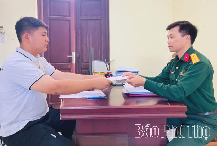 Thanh niên Nguyễn Thế Tùng, thôn Vĩnh Đông 2 trao lá đơn tình nguyện lên đường nhập ngũ cho cán bộ Ban CHQS xã.