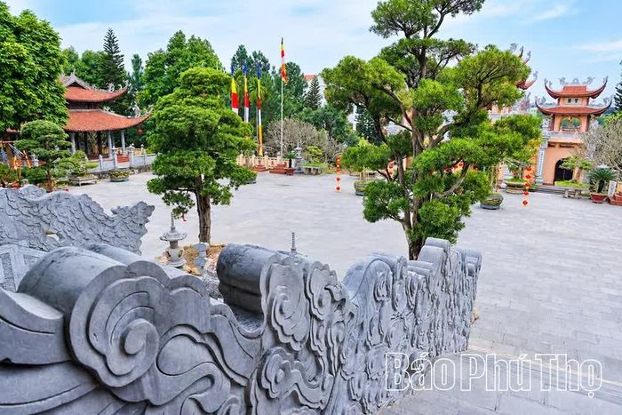 Lan can đá với những hoa văn cuộn mây tinh xảo dẫn lối xuống sân chùa, cho thấy sự kết hợp hài hòa giữa nghệ thuật trang trí kiến trúc và cảnh quan xanh mát.