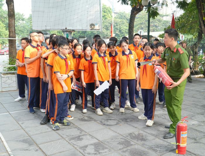 Cán bộ hướng dẫn học sinh sử dụng bình chữa cháy. Ảnh: Tùng Lâm