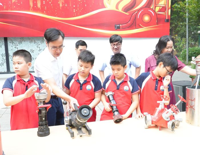Cán bộ hướng dẫn học sinh tìm hiểu, sử dụng các loại vòi chữa cháy. Ảnh: Tùng Lâm