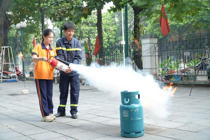 Cán bộ hướng dẫn học sinh sử dụng bình chữa cháy. Ảnh: Tùng Lâm