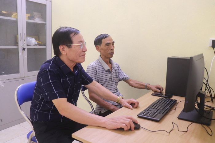 Ông Phạm Ngọc Quế, Trưởng ban Công tác Mặt trận Tổ dân phố 13 (bên trái) ứng dụng công nghệ thông tin trong công việc. Ảnh: PV
