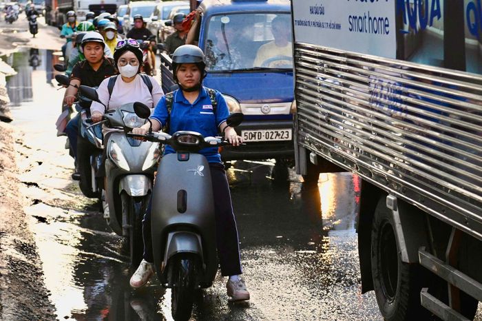  Người dân di chuyển chậm qua đoạn dưới chân cầu Phú Mỹ. Triều cường ngập hơn nửa bánh xe. 