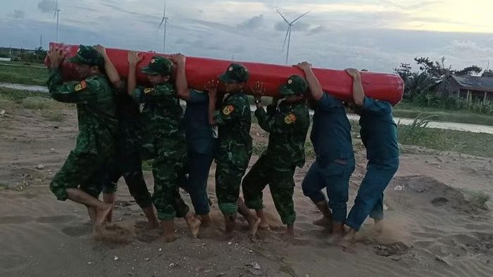 Lực lượng tại chỗ dùng bạt ni-lông gia cố đê bao. (Ảnh: TRẦN GIỎI)