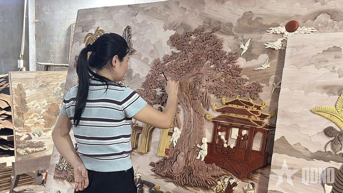  Chị Huyền tỉ mỉ vẽ hoàn thiện các chi tiết trên bức tranh ghép gỗ.