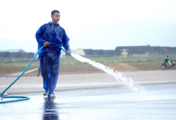  Công nhân đội mưa, phun nước vệ sinh đường băng trước ngày khánh thành 