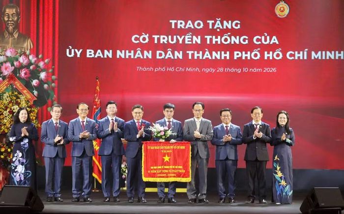 Ông Nguyễn Mạnh Cường, Phó Chủ tịch UBND TPHCM, trao cờ truyền thống của UBND TPHCM và Bộ trưởng Bộ GD&ĐT Hoàng Minh Sơn tặng hoa chúc mừng Đại học Kinh tế TPHCM. Ảnh: UEH