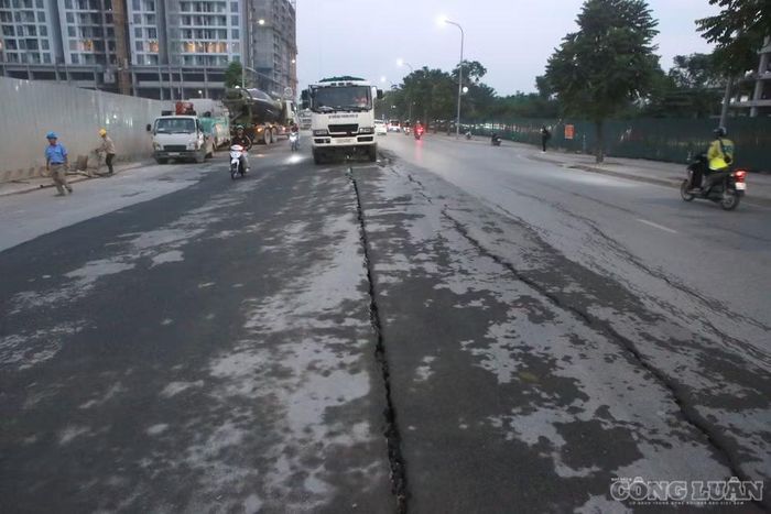 Một đoạn mặt đường bị lõm xuống, tạo thành các rãnh nứt lớn giữa đường nhựa.