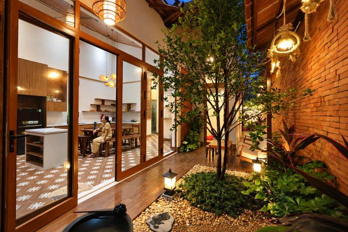 Không gian ấm cúng từ ngoài vào trong nhờ sự kết hợp hài hòa giữa vật liệu xây dựng truyền thống với cây xanh và hệ đèn vàng