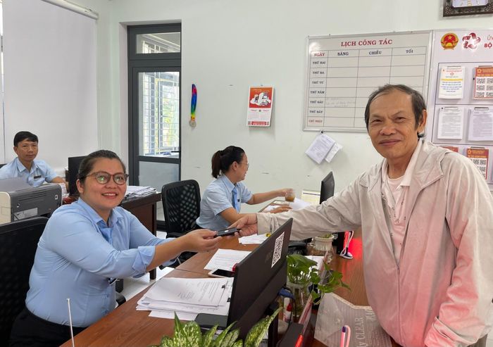 Cán bộ đưa thẻ báo rung cho người dân sau khi nộp hồ sơ tại Trung tâm Phục vụ hành chính công phường An Cựu. Ảnh: Lê Bằng