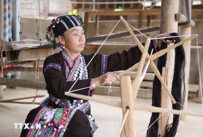 Xe sợi một trong những khâu đòi hỏi sự tỉ mỉ trước khi dệt ra những tấm vải thổ cẩm để may váy, áo. (Ảnh: Quý Trung/TTXVN)