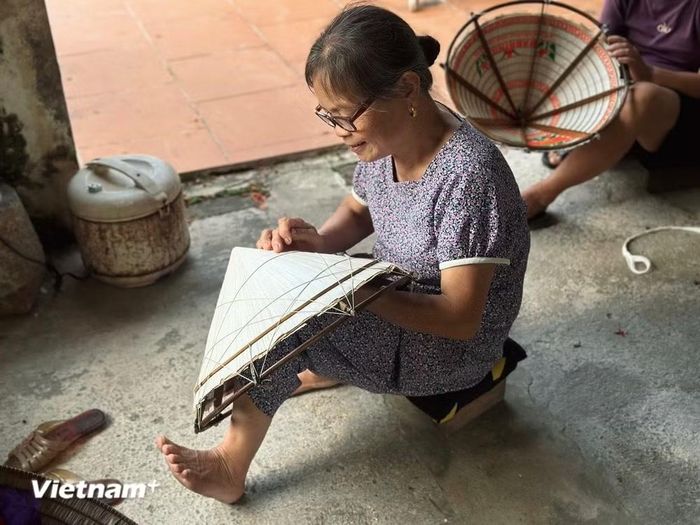 Gắn bó 50 năm với nghề, người thợ làng nghề Đào Khê vẫn miệt mài khâu từng chiếc nón bằng đôi tay khéo léo. (Ảnh: Hồng Ngọc/Vietnam+)