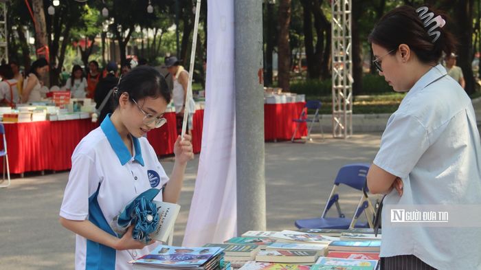 Trần Minh Khuê (trái) đang lựa chọn cuốn sách mới sau khi mang sách cũ tới đổi (Ảnh: Quốc Tiệp).