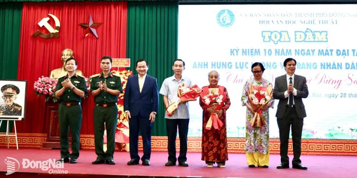 Đại diện Ban Tổ chức tọa đàm tặng hoa cảm ơn gia đình cố Đại tá, Anh hùng Lực lượng vũ trang nhân dân Lê Bá Ước. Ảnh: Nguyệt Hà