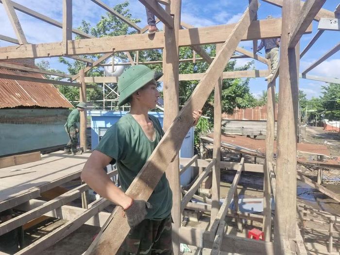 Cán bộ, chiến sĩ Trung đoàn 991 giúp gia đình người dân tháo dỡ nhà sàn chuyển đến khu tái định cư buôn Tơ Khế (xã Ia Tul). Ảnh: Dung Hoàng