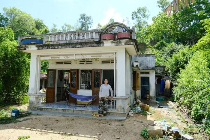  Bà Nguyễn Thị Phượng (thôn Đức Phổ, xã Đề Gi) bên cạnh căn nhà cũ có những ký ức đau buồn. Ảnh: P.L 