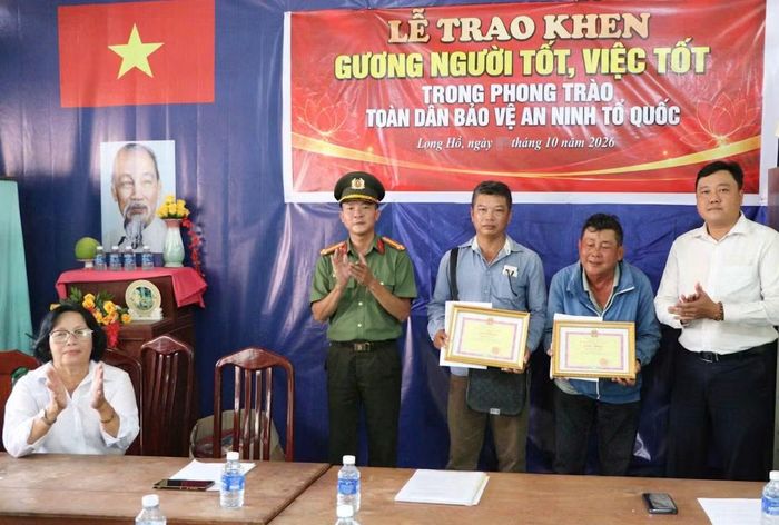 Công an xã Long Hồ trao giấy khen của Chủ tịch UBND xã tặng anh Trương Công Minh và anh Đặng Hồng Phúc.