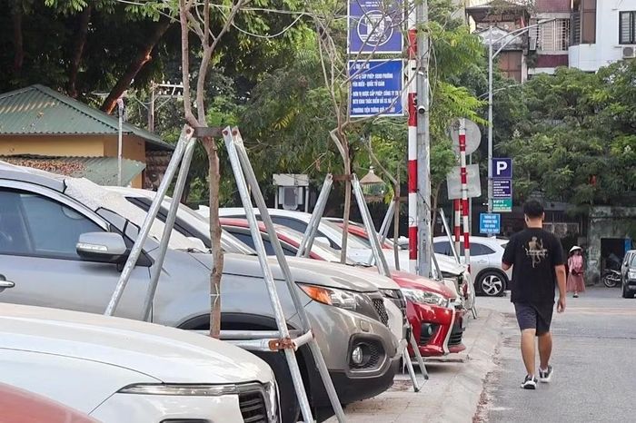 Một điểm trông giữ xe của Công ty TNHH MTV Khai thác điểm đỗ xe để ô tô kín vỉa hè, khiến người đi bộ phải xuống lòng đường.