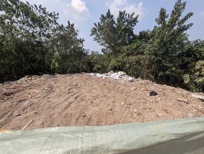 Rác thải sau khi san gạt xuống ven đường đã được lấp kín bằng đất đá, trạc thải bên trên. Ảnh: Hồng Quý