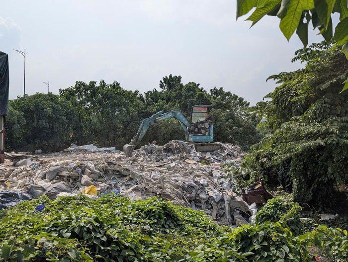 Chiếc máy múc màu xanh này ngang nhiên san gạt tại bái thải trước cổng chung cư Drean Town vào chiều 27-10. Ảnh: Hồng Quý