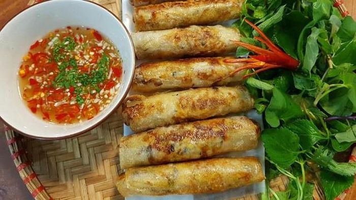 Nem rán sau khi chế biến đạt độ vàng giòn rụm, xếp bên đĩa rau sống và bát nước chấm chua ngọt thơm ngon.