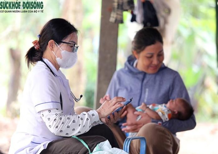 Cán bộ Trạm y tế xã Môn Sơn sử dụng điện thoại để cập nhật dữ liệu trên phần mềm tiêm chủng quốc gia, phục vụ quản lý thông tin và theo dõi lịch tiêm vaccine của trẻ em người Đan Lai ở các bản vùng sâu. Ảnh: V. Đồng