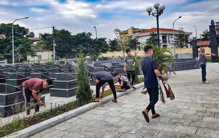 Các thiếu niên tự tay nhổ cỏ giữa các hàng mộ phần và ôm từng bó cành lá khô đi thu gom tại nghĩa trang liệt sĩ.